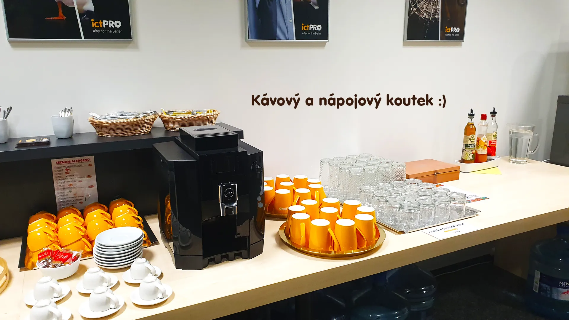 Coffee station featuring an automatic coffee machine, yellow and white cups, glasses, and syrups.