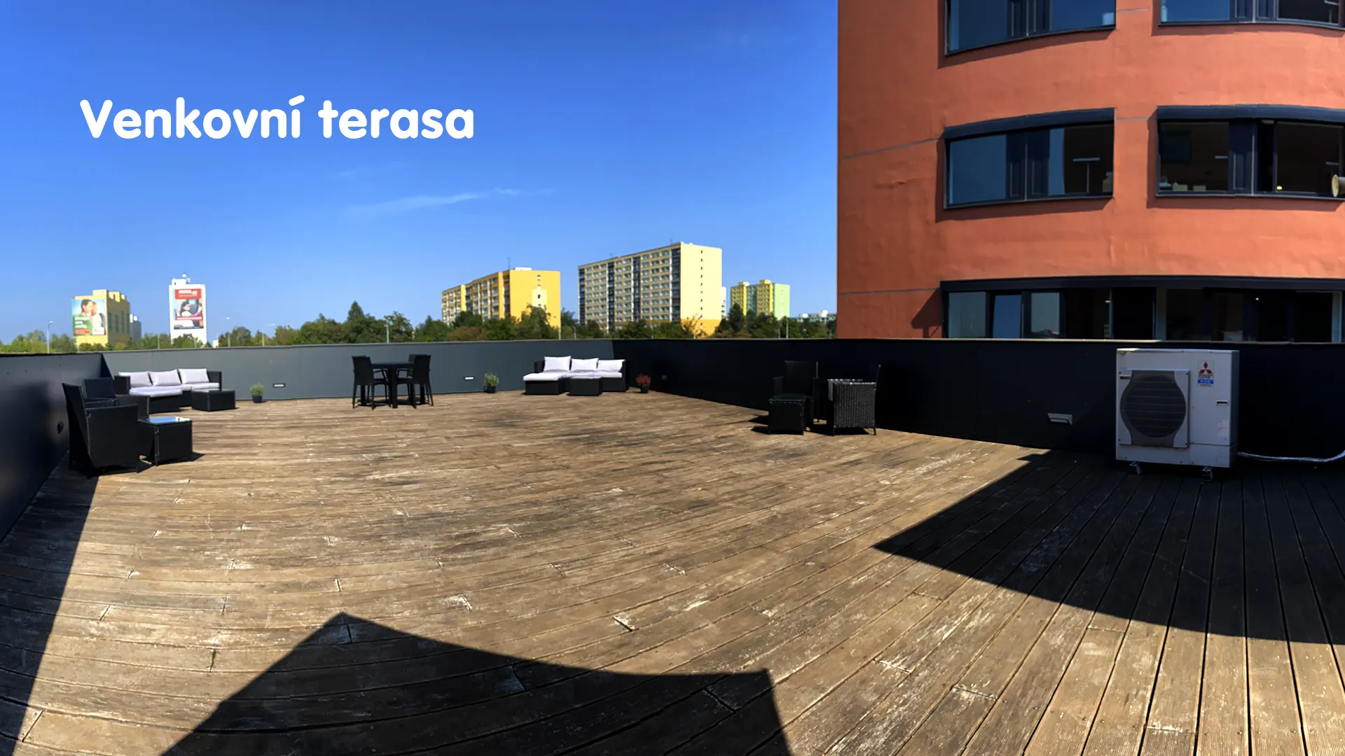 Spacious outdoor wooden terrace with seating and views of the surrounding area.