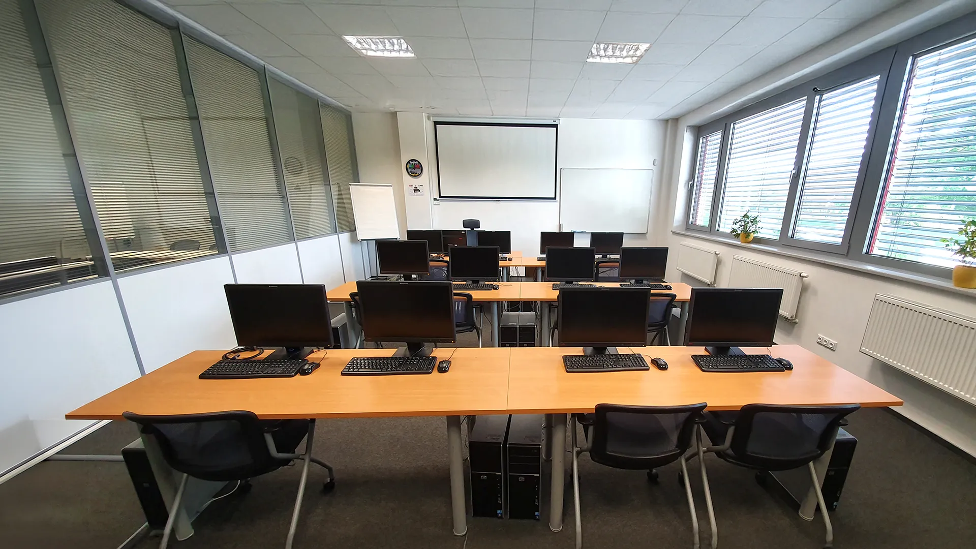 IT classroom with desks, computer monitors, and a projection screen at the front.
